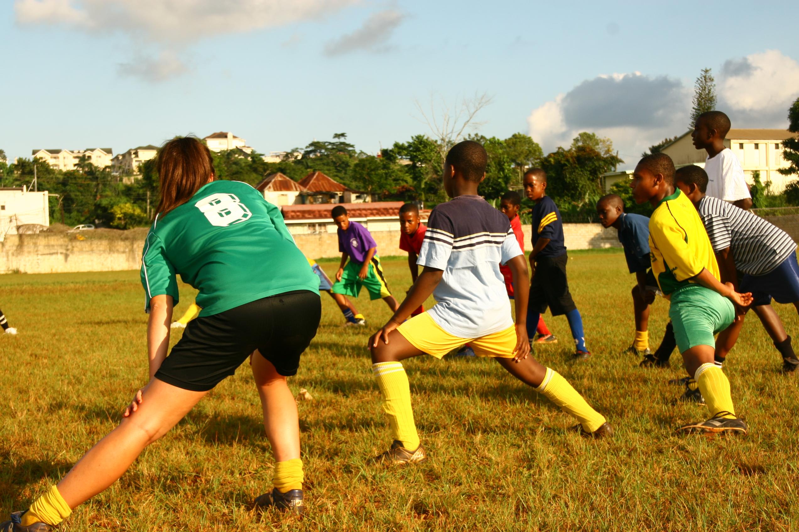 A Projects Abroad volunteer coaching sports in schools in Jamaica demonstrates a warm up stretch A volunteer taking football classes gains sports coaching work experience in Jamaica